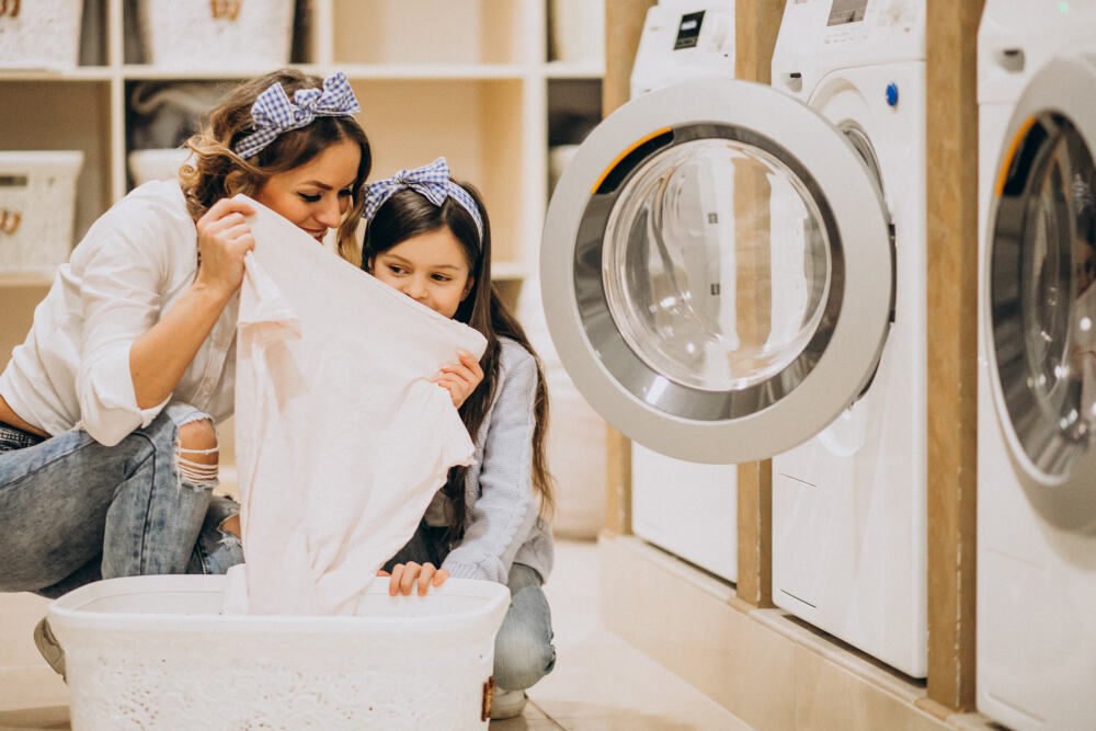 Happy mother and daughter in laundry washing cloths